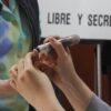 Funcionario de casilla aplica tinta electoral en el pulgar de un votante,
