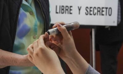 Funcionario de casilla aplica tinta electoral en el pulgar de un votante,