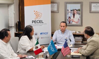 Héctor Contreras, director del SAT en Quintana Roo con tres personas y con un retrato de Mara Lezama