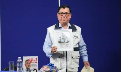 Edmundo Cázares, periodista, sosteniendo una caricatura suya
